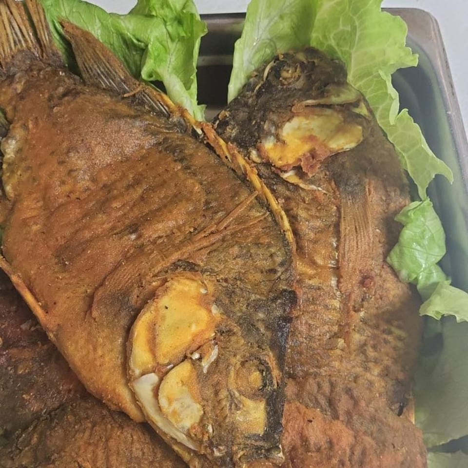 Two whole fried fish with crispy skin, garnished with fresh green lettuce.